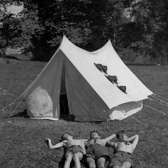 Scouterna vilar framför tältet - obs scouthattarna på tältet